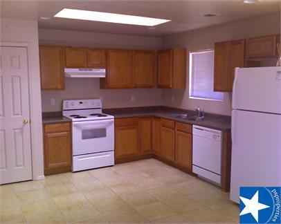 kitchen featuring dark countertops, a sink, brown cabinetry, white appliances, and under cabinet range hood