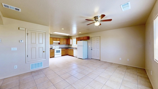 504 Maple Ave, Moriarty, NM 87035 - kitchen with white appliances, under cabinet range hood, ceiling fan, light tile patterned floors, and baseboards