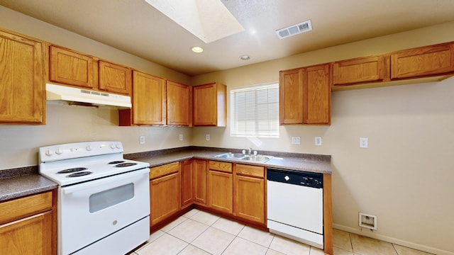 504 Maple Ave, Moriarty, NM 87035 - kitchen with white appliances, under cabinet range hood, a sink, a skylight, and dark countertops