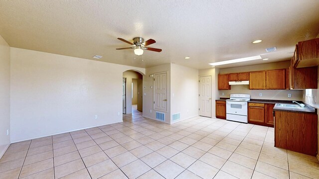 504 Maple Ave, Moriarty, NM 87035 - kitchen featuring white electric range oven, under cabinet range hood, ceiling fan, arched walkways, and dark countertops