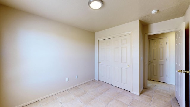 504 Maple Ave, Moriarty, NM 87035 - unfurnished bedroom featuring baseboards, light tile patterned floors, and a closet