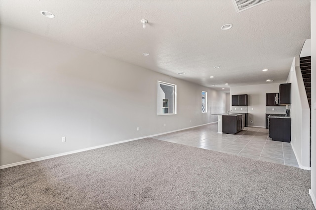 6814 Atherstone Ln NW, Albuquerque, NM 87114 - unfurnished living room with light colored carpet, a textured ceiling, baseboards, recessed lighting, and light tile patterned floors