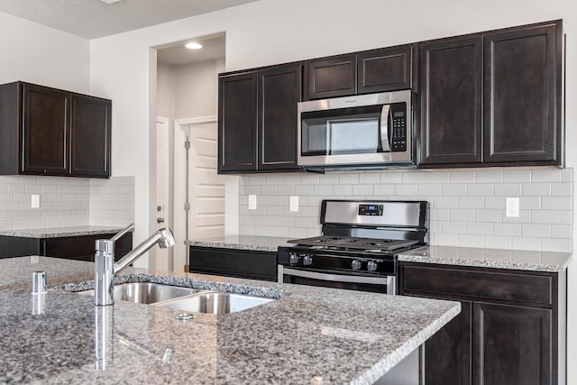 6814 Atherstone Ln NW, Albuquerque, NM 87114 - kitchen featuring stainless steel appliances, a sink, decorative backsplash, light stone counters, and dark brown cabinets