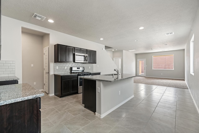 6814 Atherstone Ln NW, Albuquerque, NM 87114 - kitchen with stainless steel appliances, a sink, decorative backsplash, light tile patterned flooring, and a textured ceiling