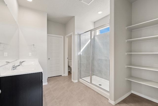6814 Atherstone Ln NW, Albuquerque, NM 87114 - bathroom featuring double vanity, a stall shower, tile patterned flooring, toilet, and a textured ceiling