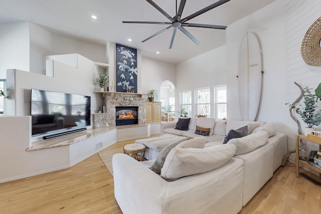 122 Martha Ct, Corrales, NM 87048 - living area with light wood-style floors, a fireplace, a ceiling fan, and a towering ceiling