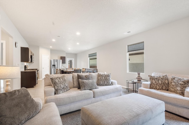 living area with recessed lighting, baseboards, and light colored carpet
