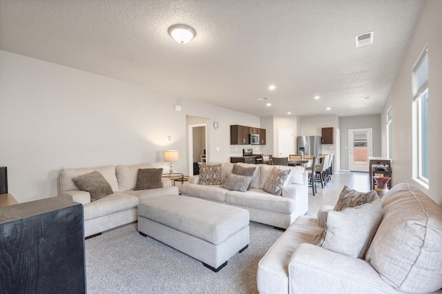 living room featuring recessed lighting, a textured ceiling, and visible vents
