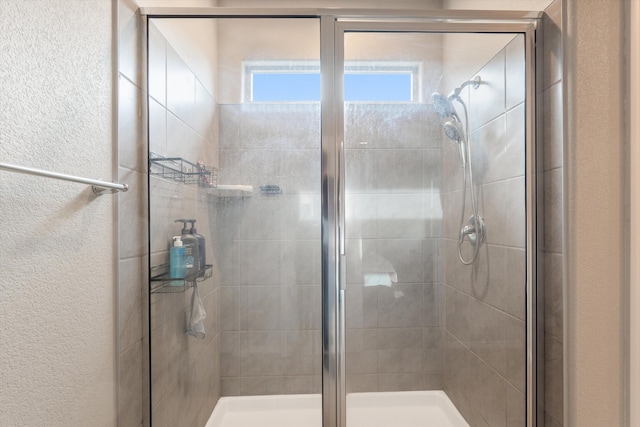 bathroom with a textured wall and a shower stall