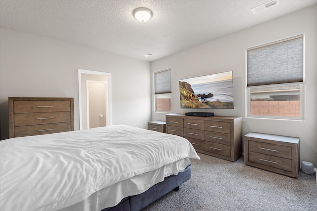 bedroom featuring light colored carpet, a textured ceiling, and visible vents