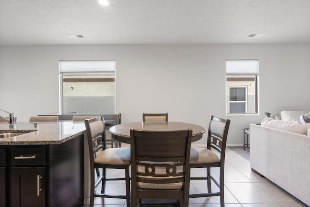 dining area with light tile patterned floors, a textured ceiling, and visible vents
