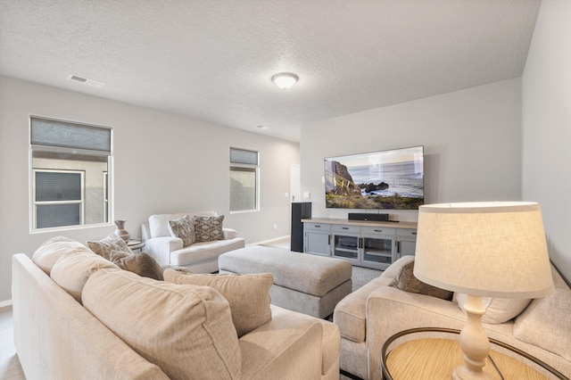 living room with baseboards, a textured ceiling, and visible vents
