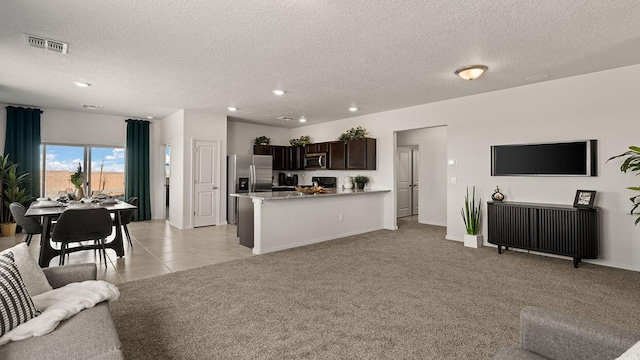 living room with a textured ceiling, visible vents, light carpet, and baseboards