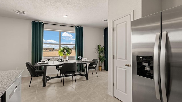 dining space with baseboards, a textured ceiling, visible vents, and light tile patterned floors