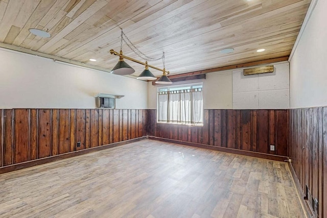 empty room with wooden ceiling, wooden walls, wood finished floors, and a wainscoted wall