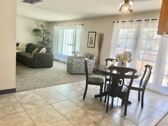 dining area with light carpet, light tile patterned floors, a ceiling fan, and visible vents
