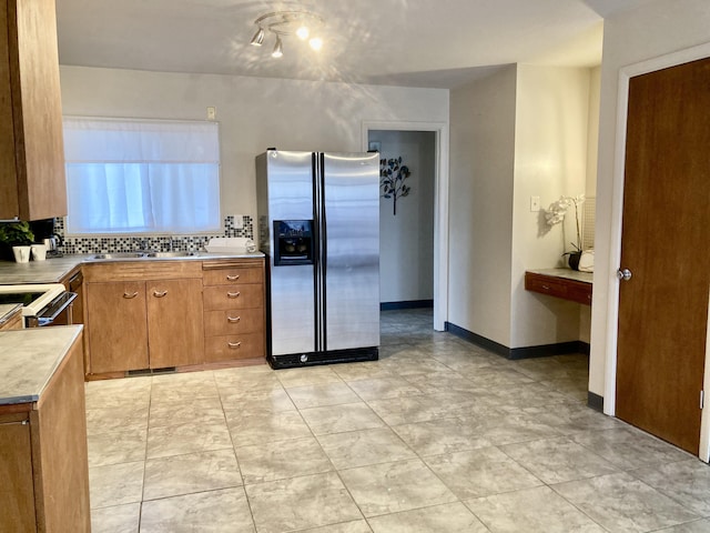 kitchen with brown cabinetry, tasteful backsplash, stainless steel fridge with ice dispenser, and light countertops