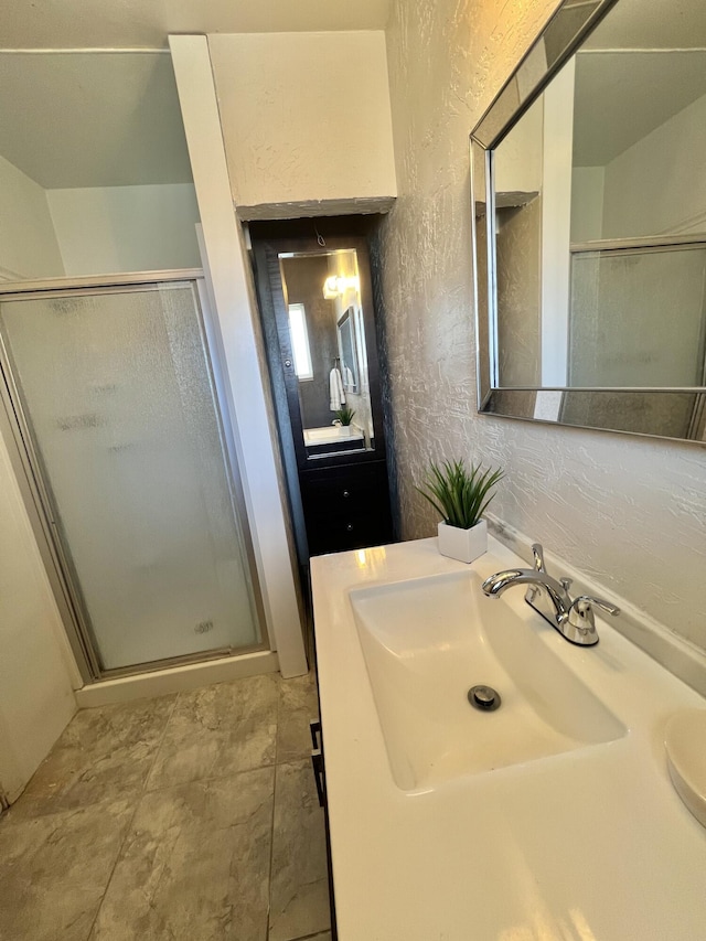 full bath with a stall shower, a textured wall, and vanity