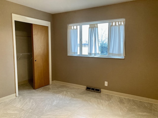 unfurnished bedroom featuring visible vents, a closet, and baseboards