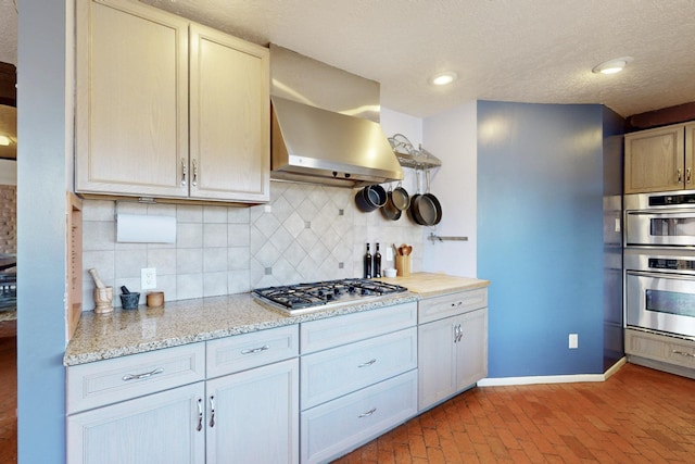 1005 Guadalupe Del Prado St NW, Albuquerque, NM 87107 - kitchen featuring wall chimney exhaust hood, stainless steel appliances, brick floor, baseboards, and backsplash
