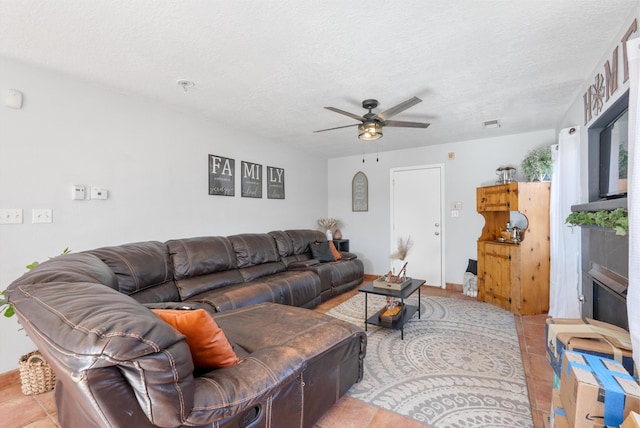living room featuring tile patterned floors, ceiling fan, visible vents, and a textured ceiling