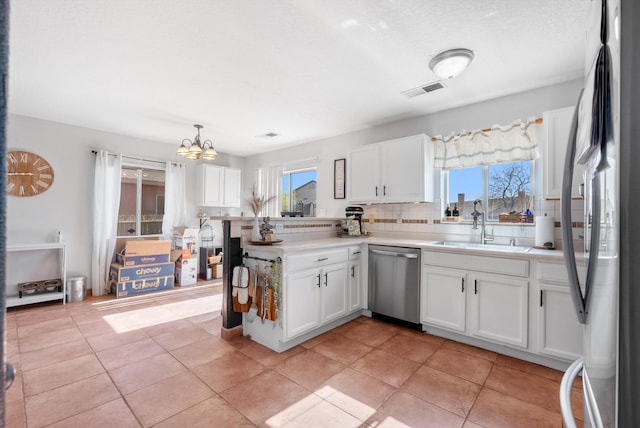 kitchen with stainless steel appliances, an inviting chandelier, white cabinetry, and a sink