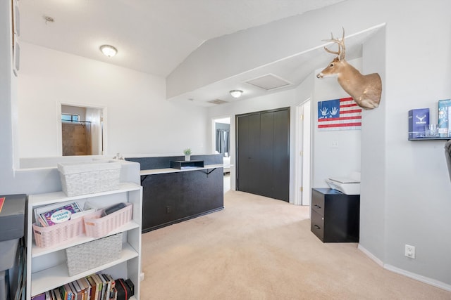 interior space with baseboards, carpet, vaulted ceiling, and attic access
