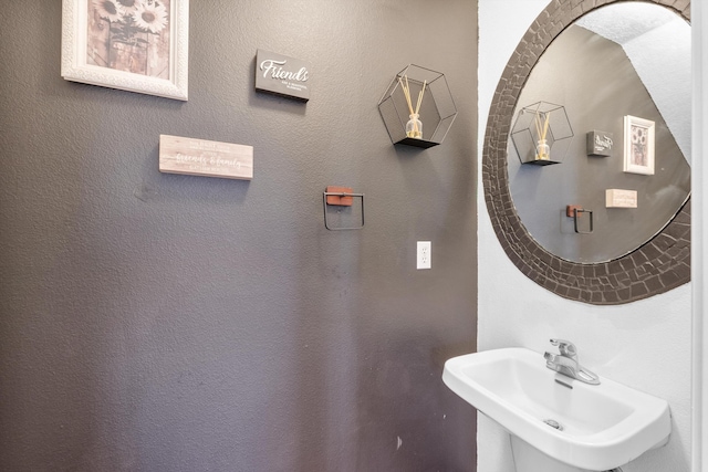 bathroom featuring a textured wall and a sink