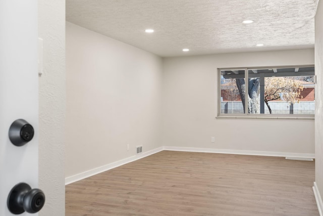 2908 Pennsylvania St NE, Albuquerque, NM 87110 - empty room with a textured ceiling, recessed lighting, baseboards, wood finished floors, and visible vents