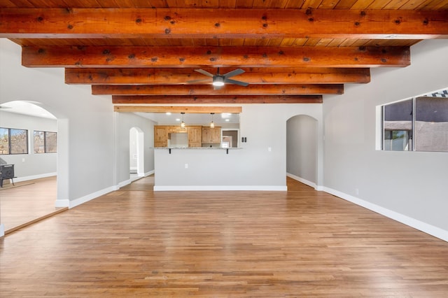 unfurnished living room featuring arched walkways, baseboards, wooden ceiling, and ceiling fan