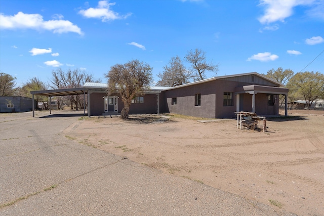 view of front facade with a carport, driveway, and stucco siding