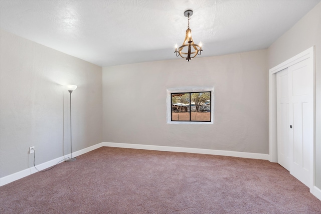 empty room featuring baseboards, a notable chandelier, and carpet