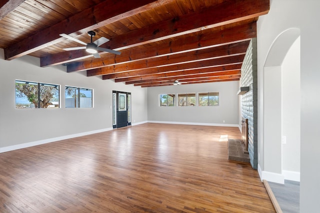unfurnished living room featuring wooden ceiling, a ceiling fan, beam ceiling, wood finished floors, and a large fireplace