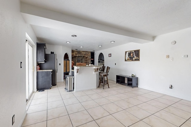 3008 Corona Dr NW, Albuquerque, NM 87120 - kitchen with a breakfast bar area, arched walkways, dark cabinetry, baseboards, and light tile patterned floors
