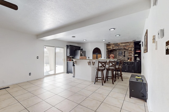 3008 Corona Dr NW, Albuquerque, NM 87120 - kitchen featuring a kitchen breakfast bar, a textured ceiling, a center island, freestanding refrigerator, and light tile patterned floors