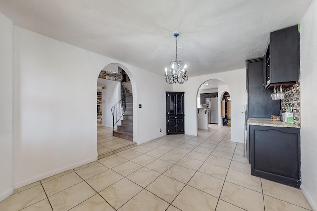 3008 Corona Dr NW, Albuquerque, NM 87120 - unfurnished dining area featuring light tile patterned flooring, baseboards, stairway, a chandelier, and arched walkways