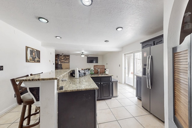 3008 Corona Dr NW, Albuquerque, NM 87120 - kitchen with ceiling fan, a kitchen bar, stainless steel refrigerator with ice dispenser, a sink, and light tile patterned floors