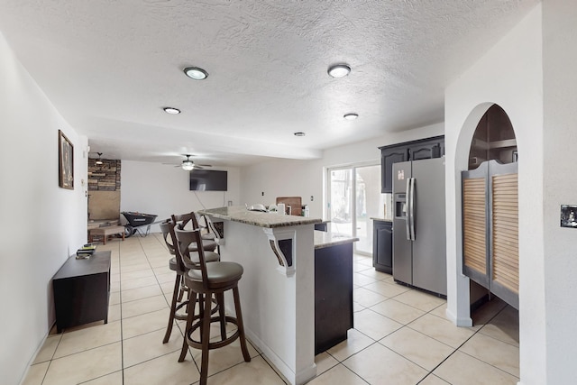 3008 Corona Dr NW, Albuquerque, NM 87120 - kitchen with stainless steel fridge with ice dispenser, a breakfast bar area, a center island, a ceiling fan, and light tile patterned floors