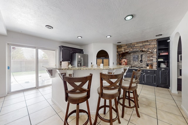 3008 Corona Dr NW, Albuquerque, NM 87120 - kitchen featuring light tile patterned floors, arched walkways, stainless steel appliances, and a kitchen bar