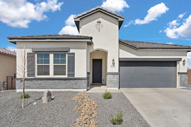 mediterranean / spanish-style home with a tiled roof, stone siding, concrete driveway, a garage, and stucco siding