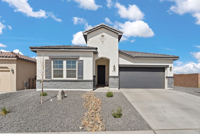 view of front of home with driveway, stone siding, a tiled roof, an attached garage, and stucco siding