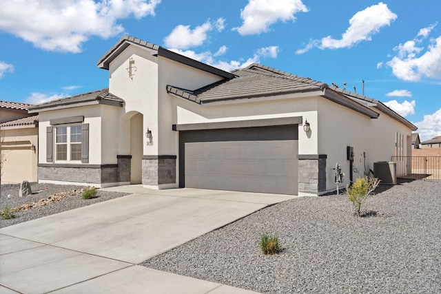 mediterranean / spanish-style house featuring stone siding, concrete driveway, stucco siding, and a garage