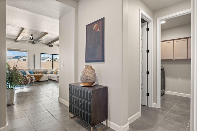 hall with baseboards, tile patterned flooring, and beam ceiling