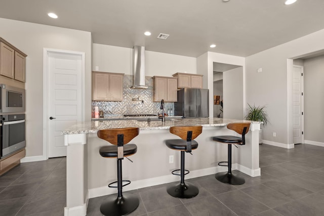 kitchen with tasteful backsplash, a sink, wall chimney exhaust hood, appliances with stainless steel finishes, and visible vents