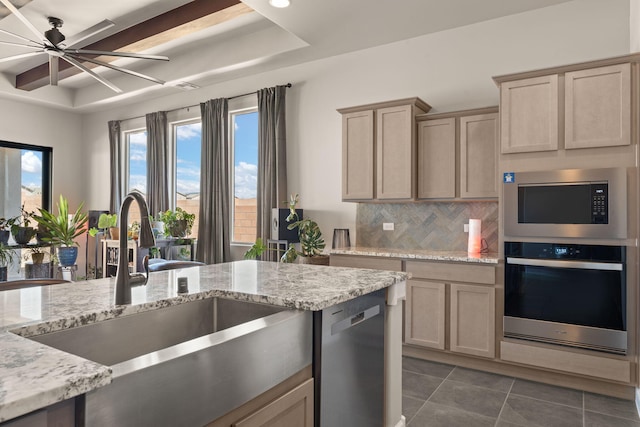 kitchen with stainless steel appliances, a ceiling fan, a sink, dark tile patterned flooring, and decorative backsplash