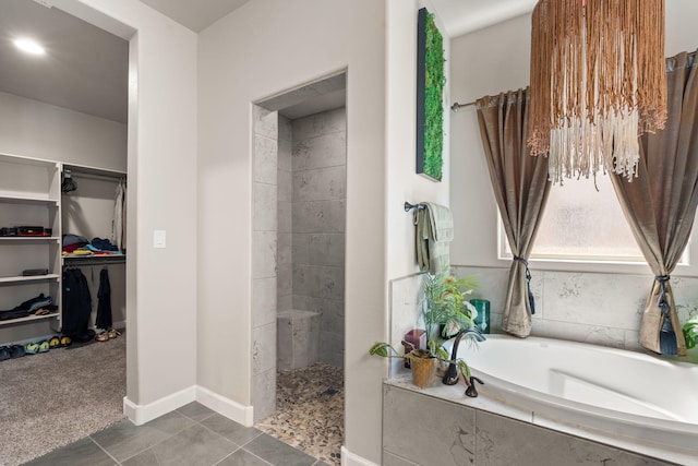 bathroom with tile patterned floors, a walk in shower, a walk in closet, baseboards, and a garden tub