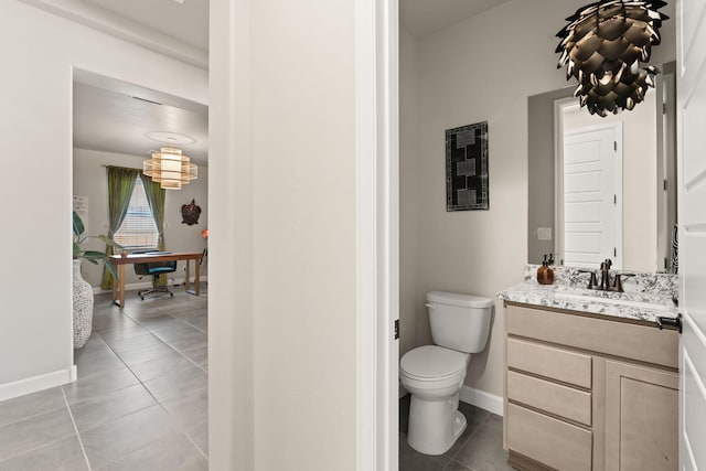 bathroom featuring toilet, vanity, tile patterned floors, and baseboards