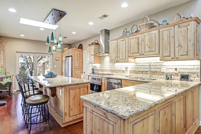kitchen with visible vents, a skylight, a sink, stainless steel appliances, and wall chimney exhaust hood