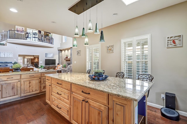 kitchen with dark wood-style flooring, open floor plan, recessed lighting, light stone counters, and hanging light fixtures