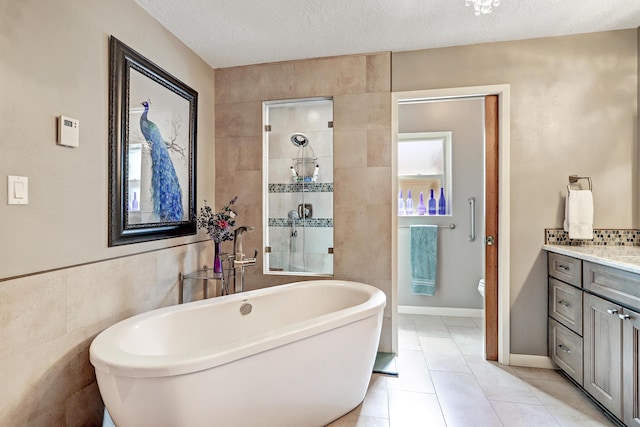 bathroom with vanity, tile walls, a textured ceiling, a soaking tub, and a tile shower